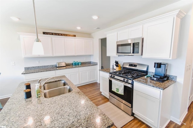 kitchen featuring white cabinets, light wood-type flooring, stainless steel appliances, and a sink