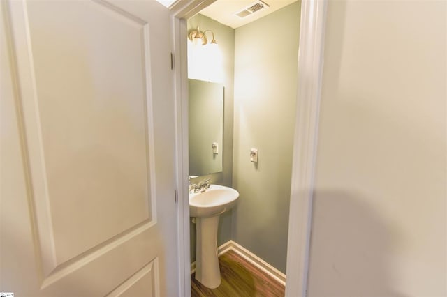 bathroom featuring a sink, wood finished floors, visible vents, and baseboards