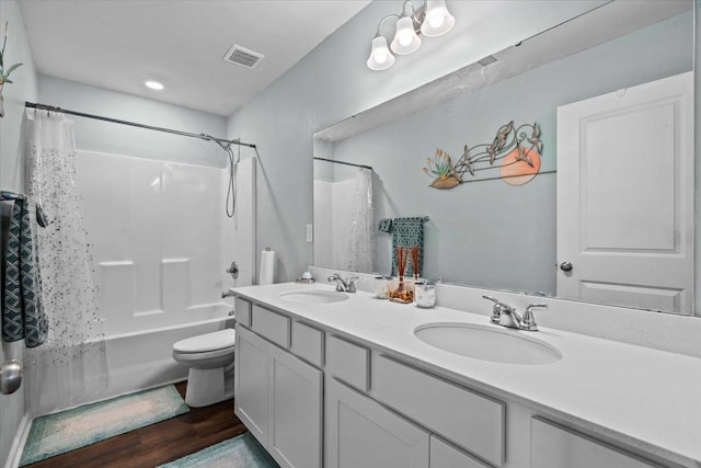 full bath featuring toilet, double vanity, a sink, and visible vents