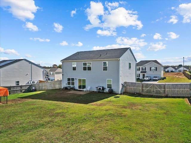 back of house with a lawn, a fenced backyard, and a residential view