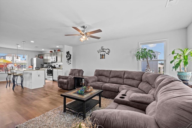 living room with light wood finished floors, a ceiling fan, and recessed lighting