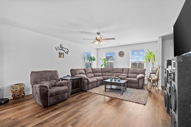 living room with ceiling fan, baseboards, and wood finished floors