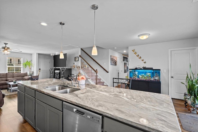 kitchen featuring light stone counters, wood finished floors, a sink, open floor plan, and stainless steel dishwasher