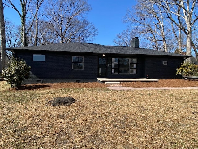 back of property featuring brick siding, a shingled roof, crawl space, a lawn, and a chimney