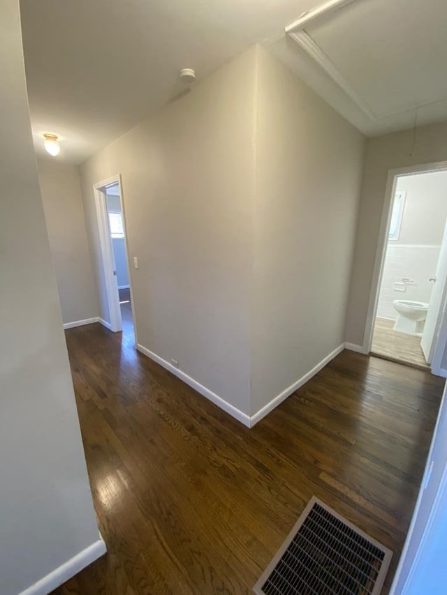 hall featuring attic access, visible vents, dark wood finished floors, and baseboards