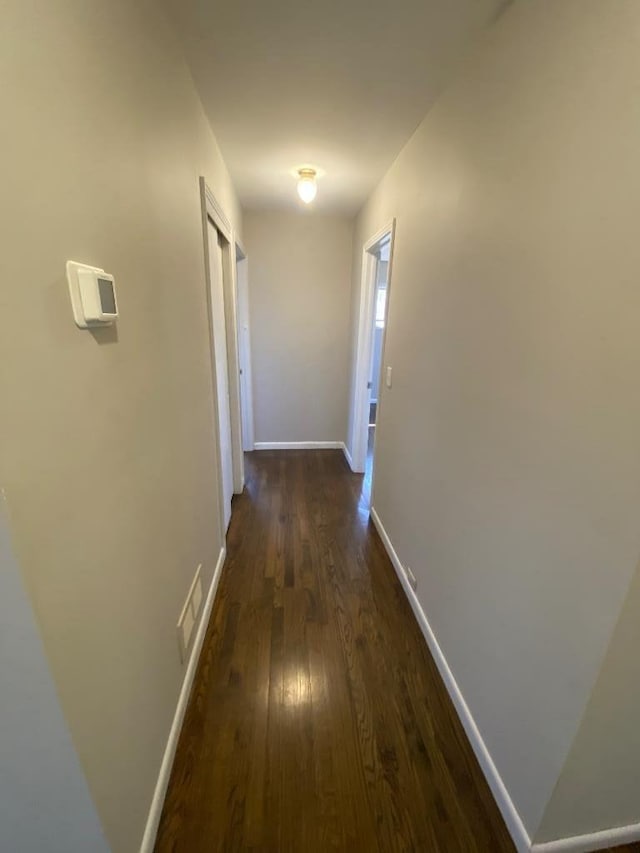 corridor featuring dark wood-style flooring and baseboards