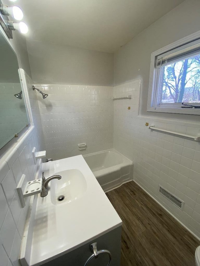 full bath with bathing tub / shower combination, tile walls, visible vents, vanity, and wood finished floors