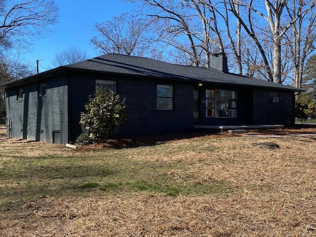 rear view of house featuring brick siding, a lawn, and a chimney