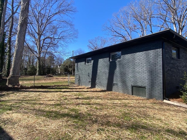 view of side of property featuring crawl space, brick siding, fence, and a lawn