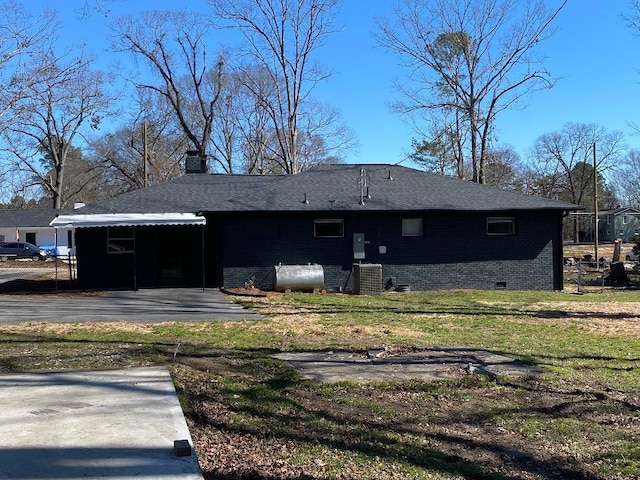 rear view of property featuring crawl space, brick siding, heating fuel, and a yard