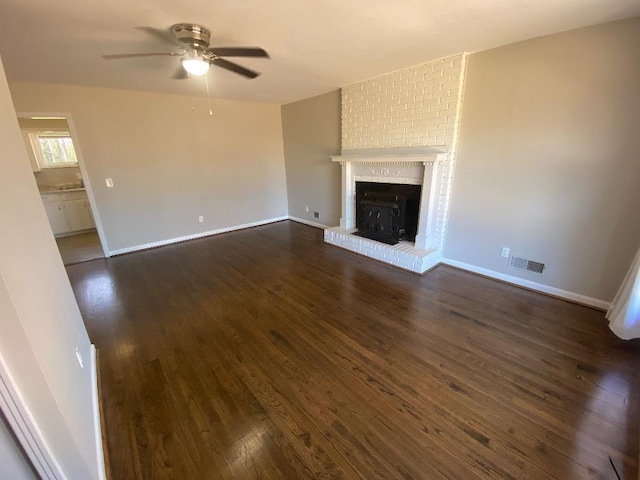 unfurnished living room with dark wood-style floors, ceiling fan, visible vents, and baseboards