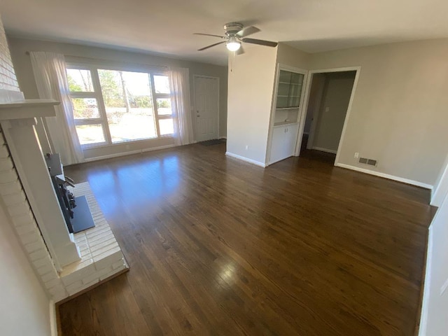 unfurnished living room featuring dark wood-style floors, visible vents, ceiling fan, and baseboards