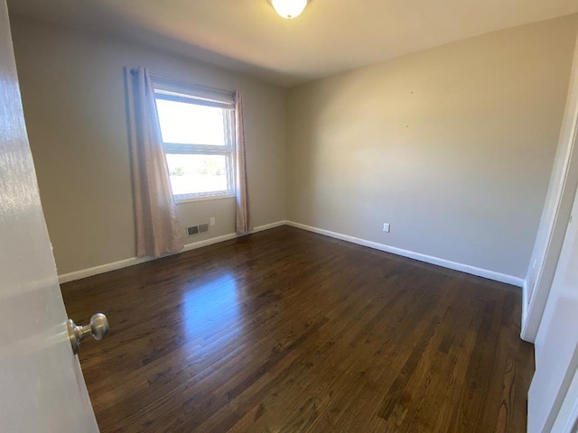 spare room featuring baseboards and dark wood-style flooring