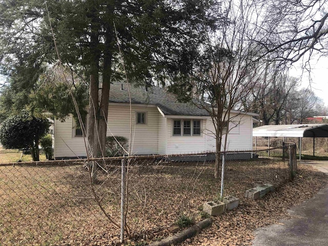 view of side of property with a shingled roof and fence