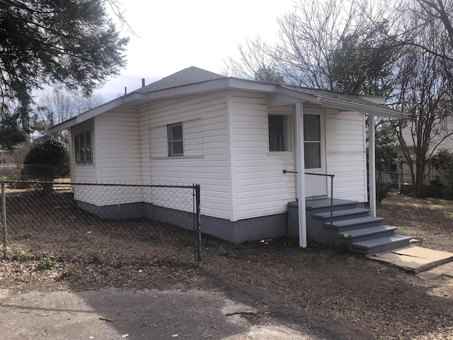 view of side of property featuring fence and roof with shingles