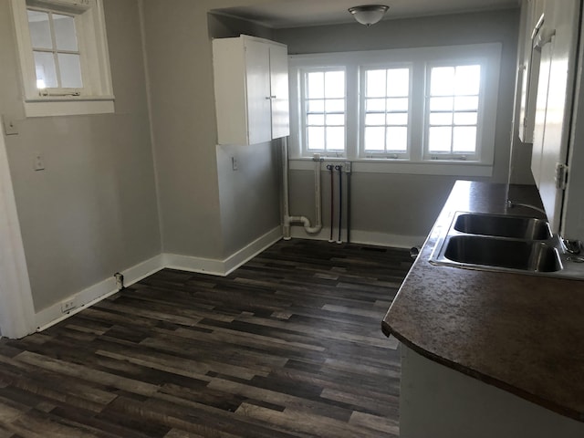 kitchen with baseboards, dark wood-style flooring, white cabinets, and a sink