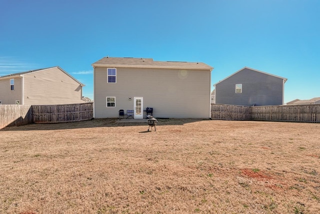 back of property with a fenced backyard and a lawn