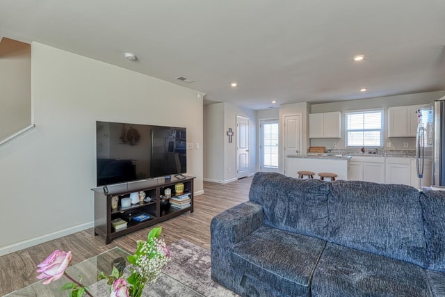 living area with light wood-type flooring, baseboards, and visible vents