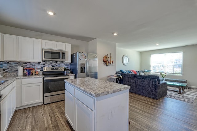 kitchen with appliances with stainless steel finishes, tasteful backsplash, light countertops, and wood finished floors