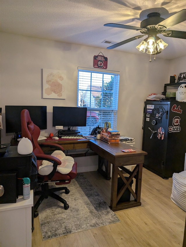 office space with light wood-style flooring, visible vents, a ceiling fan, and a textured ceiling