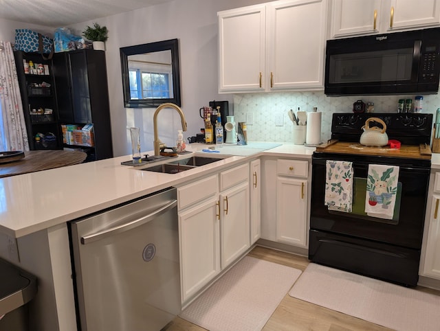 kitchen featuring a peninsula, light countertops, black appliances, white cabinetry, and a sink