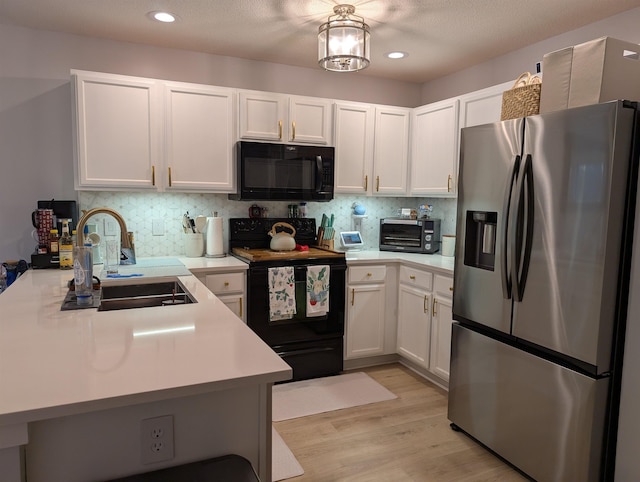 kitchen featuring black appliances, a sink, light countertops, and white cabinetry