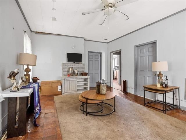 living area featuring ceiling fan and ornamental molding