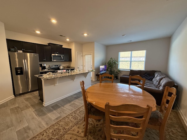 dining room with recessed lighting, visible vents, light wood-style flooring, and baseboards