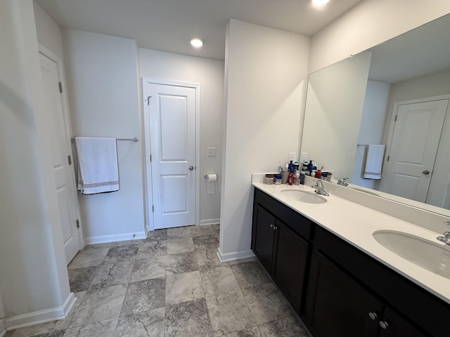 full bathroom featuring a sink, baseboards, and double vanity