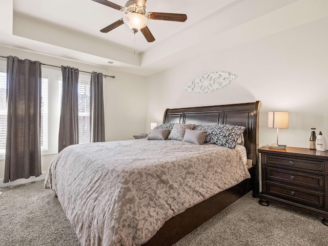 bedroom featuring a ceiling fan, a raised ceiling, carpet flooring, and visible vents