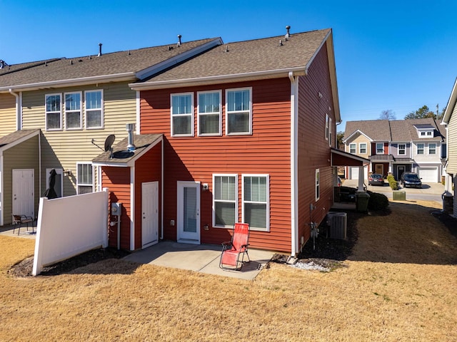 rear view of house with a patio, a yard, and roof with shingles