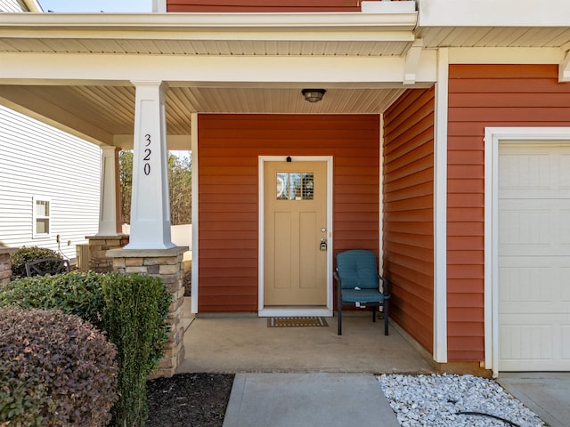 entrance to property featuring covered porch and a garage