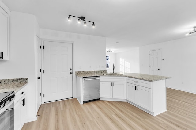 kitchen featuring light wood finished floors, white cabinets, dishwasher, a peninsula, and a sink