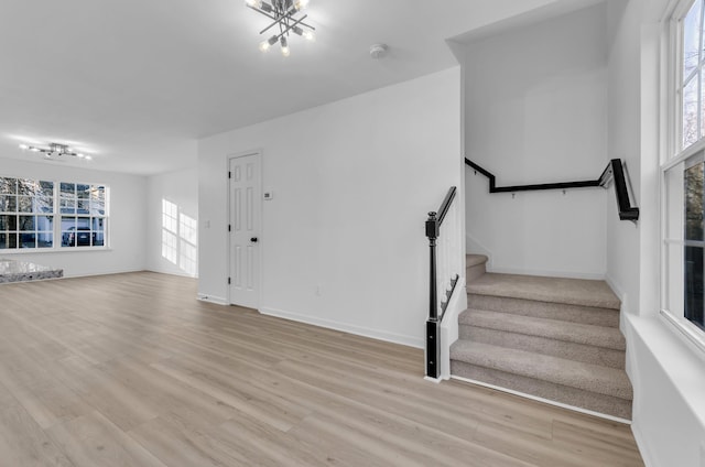 interior space with light wood finished floors, baseboards, stairway, and a notable chandelier