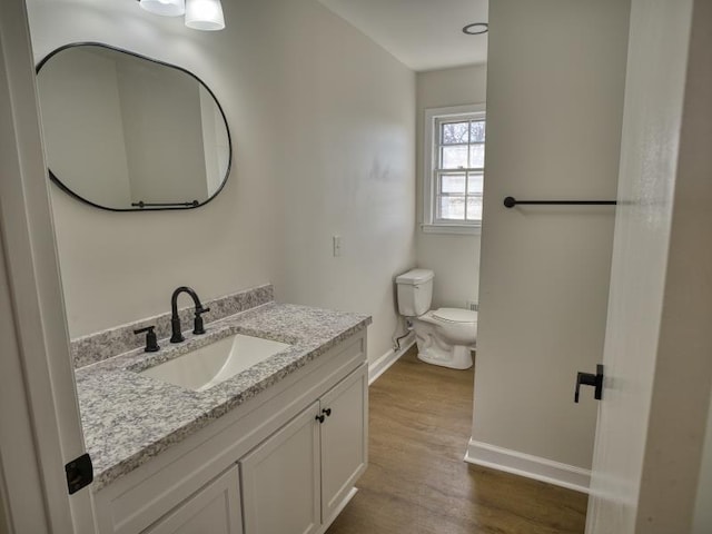 bathroom featuring baseboards, vanity, toilet, and wood finished floors