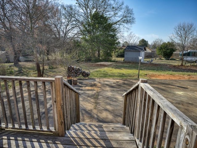 deck featuring an outbuilding, fence, a lawn, and a shed