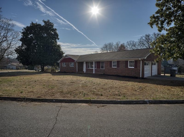 ranch-style home featuring a garage, driveway, brick siding, and a front lawn