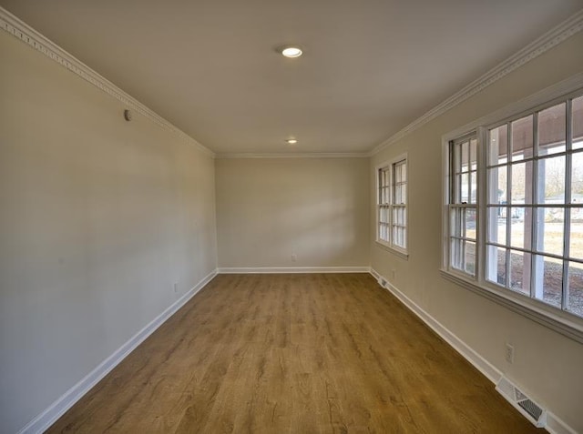 spare room featuring ornamental molding, visible vents, baseboards, and wood finished floors