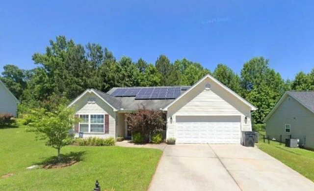 single story home with concrete driveway, an attached garage, central AC unit, roof mounted solar panels, and a front lawn