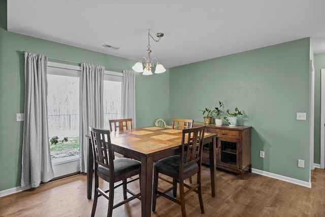 dining space with wood finished floors, visible vents, baseboards, and an inviting chandelier