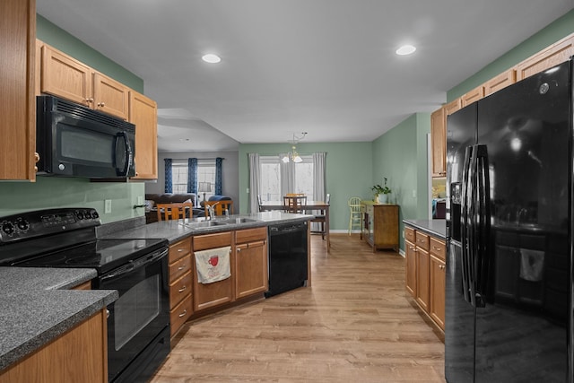 kitchen with light wood-style flooring, a peninsula, a sink, black appliances, and dark countertops