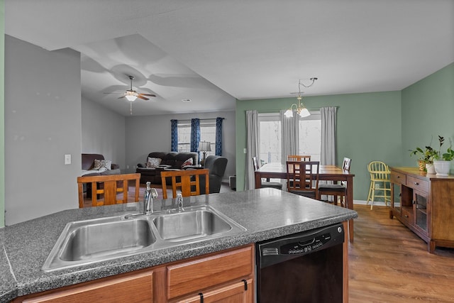 kitchen featuring wood finished floors, a sink, black dishwasher, brown cabinetry, and dark countertops