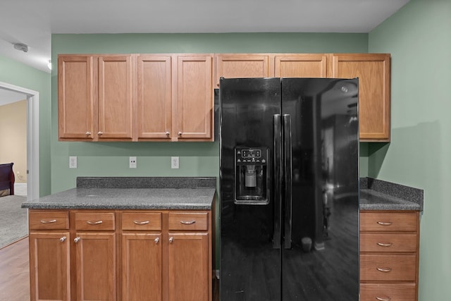 kitchen with dark countertops, light wood-type flooring, and black refrigerator with ice dispenser