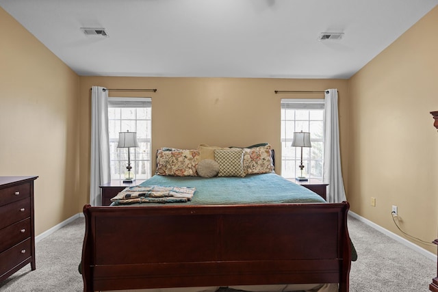 bedroom with multiple windows, visible vents, and light colored carpet