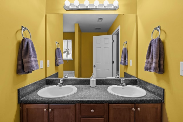 full bath featuring double vanity, a sink, and toilet