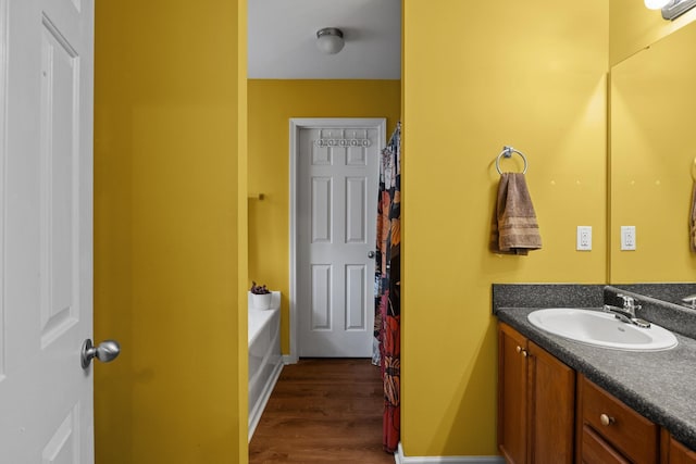 bathroom with a washtub, vanity, wood finished floors, a shower with curtain, and baseboards