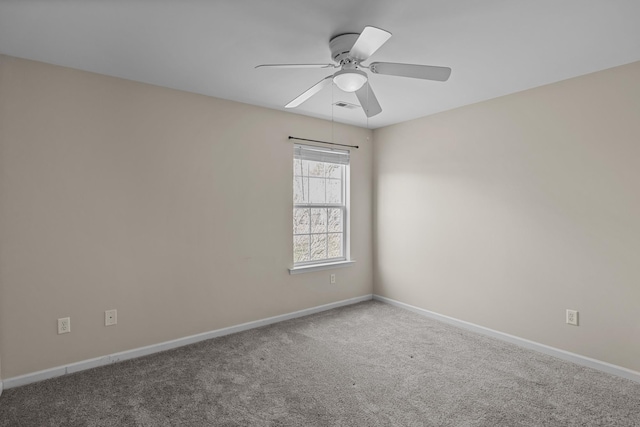 spare room featuring carpet floors, a ceiling fan, visible vents, and baseboards