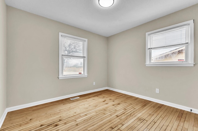 spare room with baseboards, visible vents, and hardwood / wood-style floors