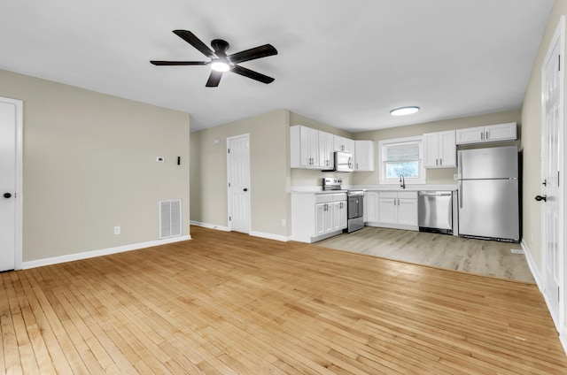 kitchen with light countertops, visible vents, appliances with stainless steel finishes, light wood-type flooring, and baseboards