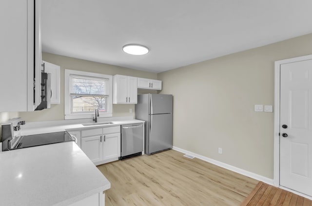 kitchen with appliances with stainless steel finishes, light countertops, white cabinetry, and a sink